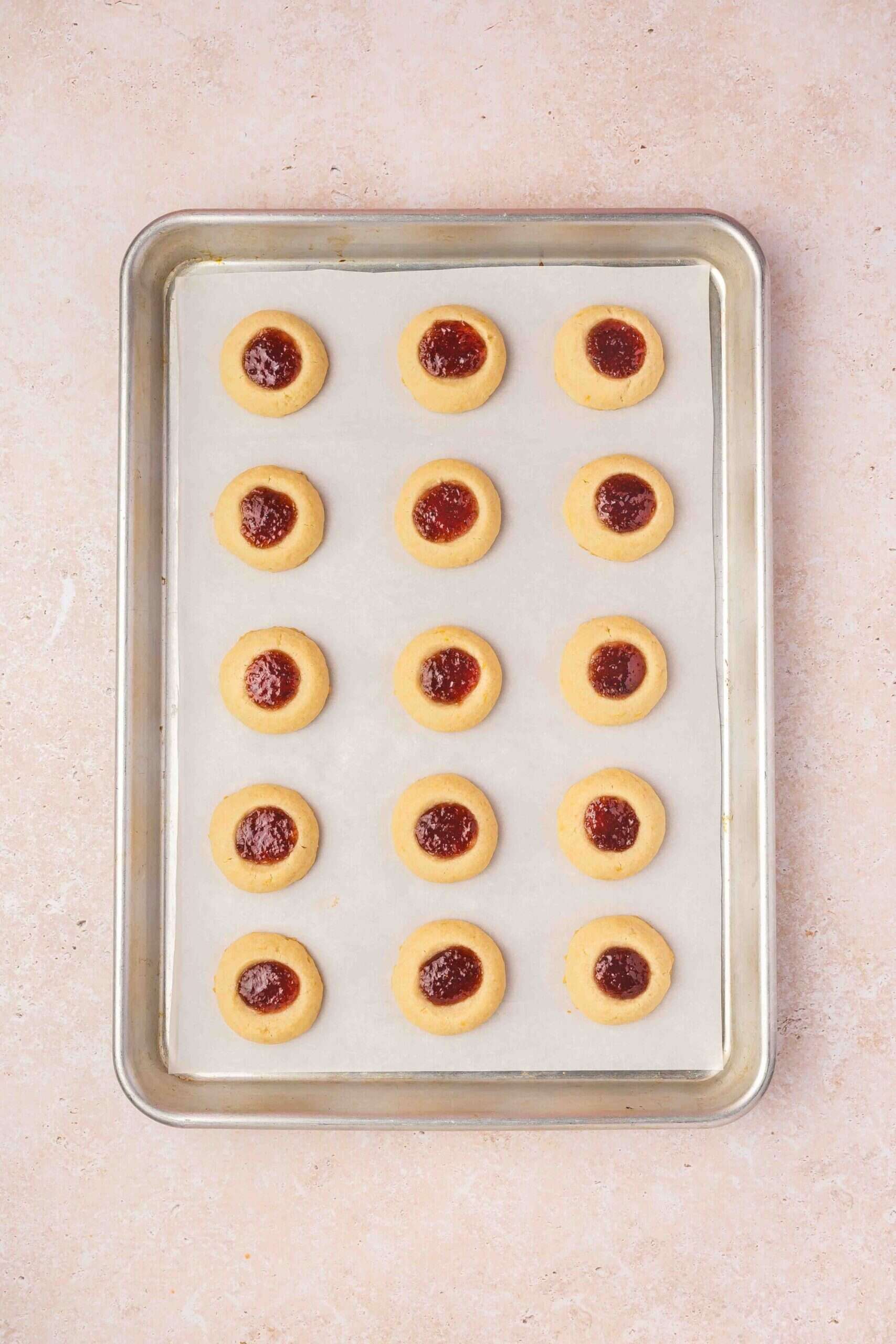 Freshly baked raspberry thumbprint cookies cooling on a wire rack after baking.