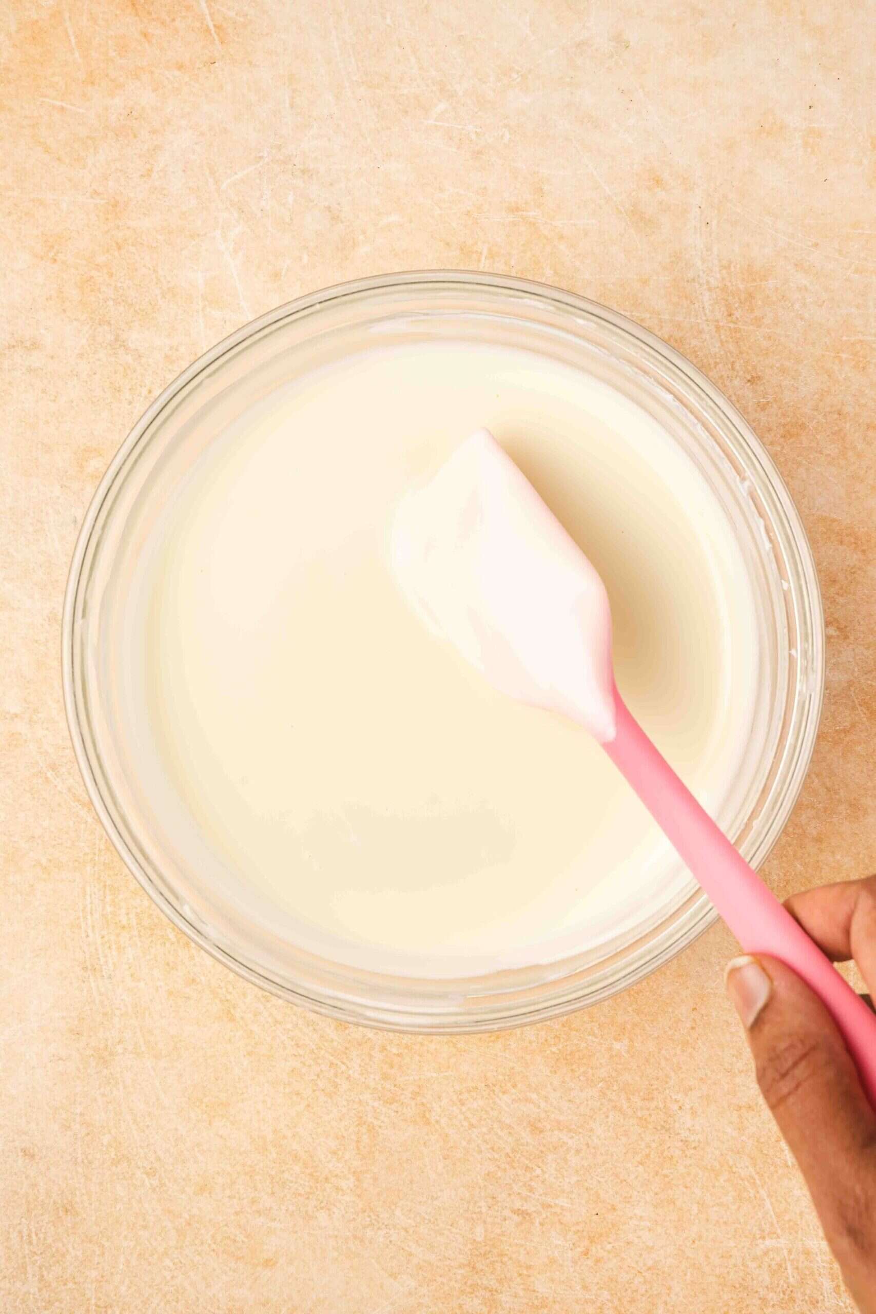 Melting white candy melts in a microwave-safe bowl for white chocolate covered Oreos.
