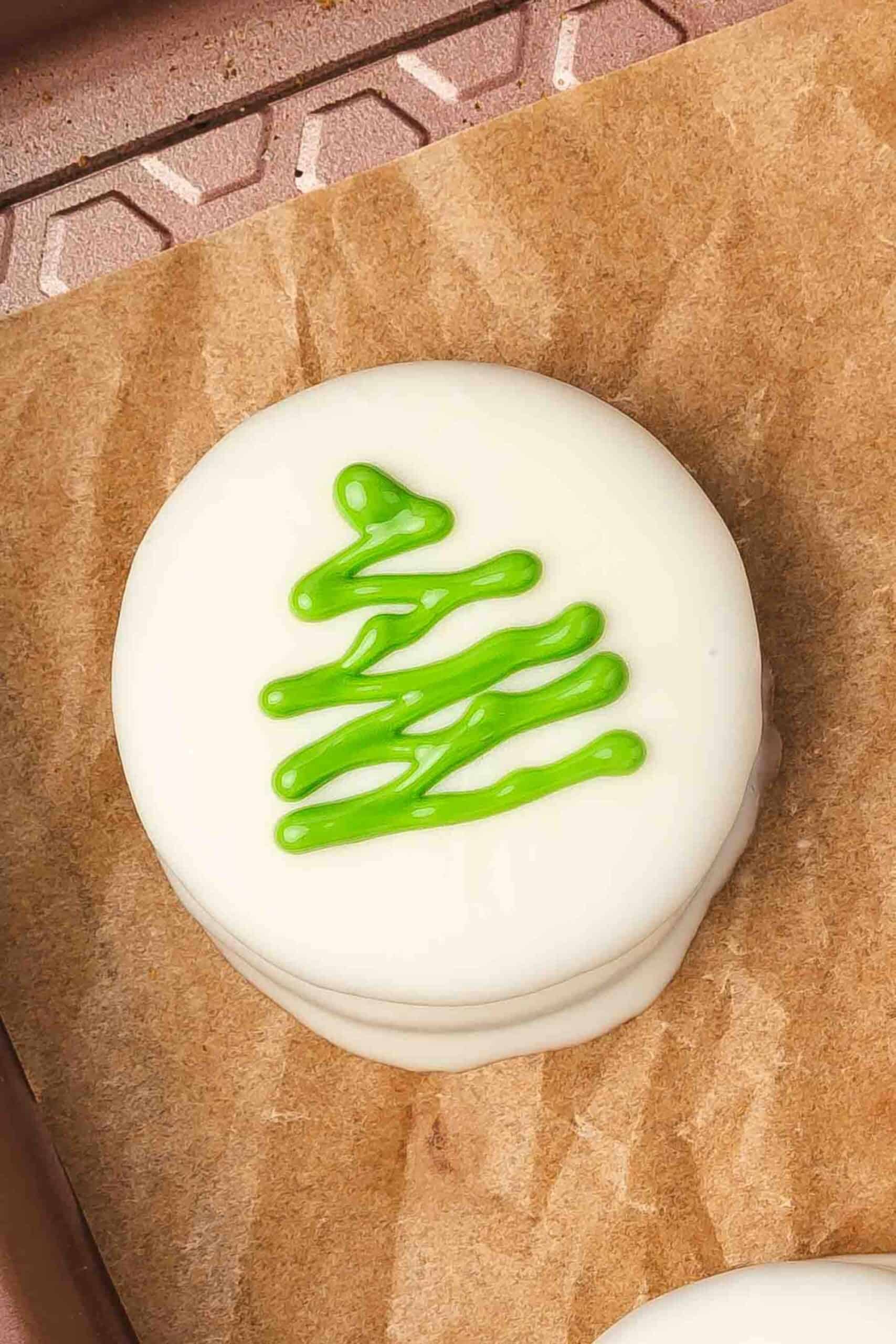 Drizzling green chocolate over white chocolate covered Oreos in a zig-zag Christmas tree pattern.