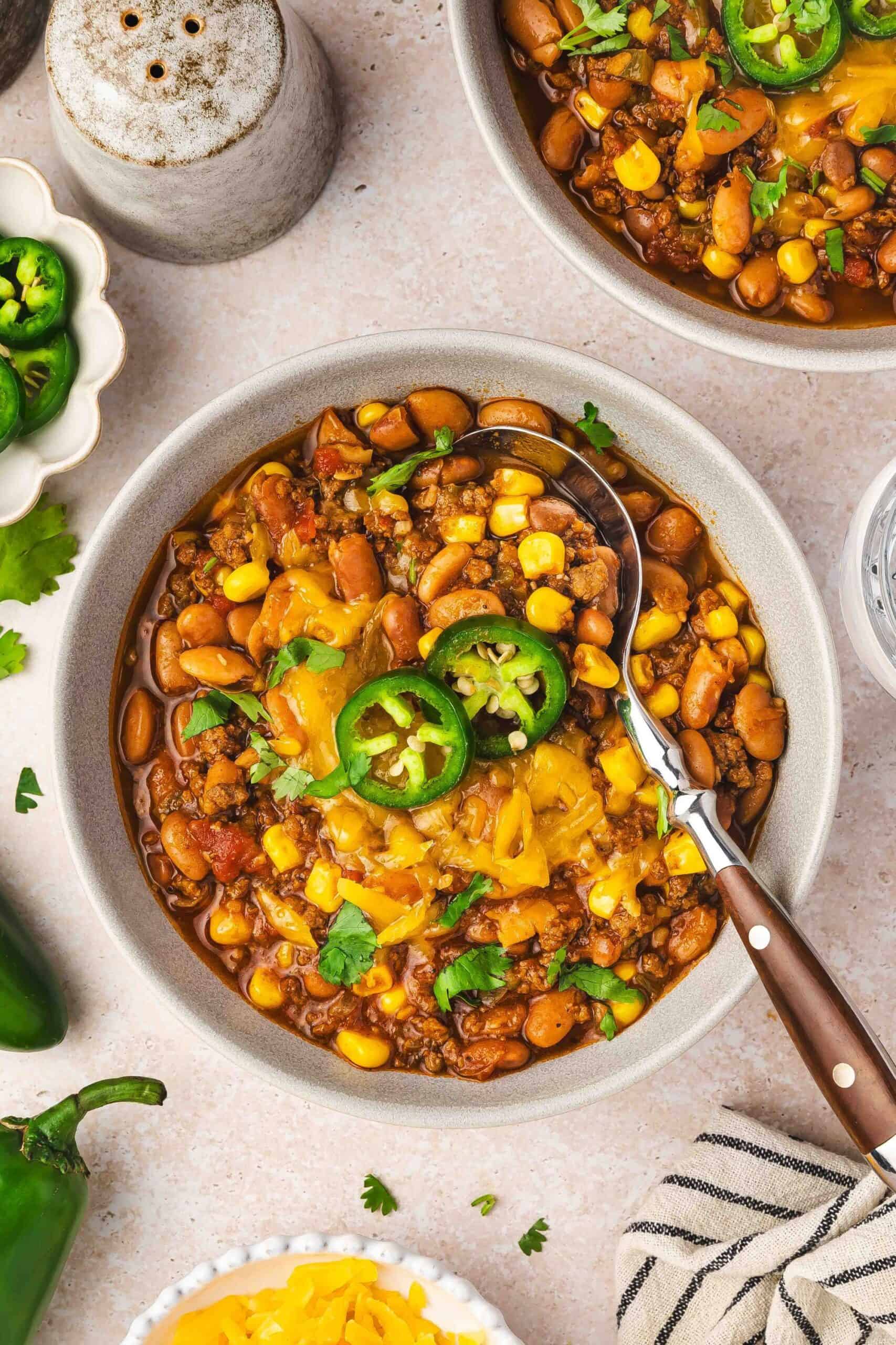 Easy homemade chili served in a bowl with shredded cheddar, jalapeno slices, and cilantro garnish.