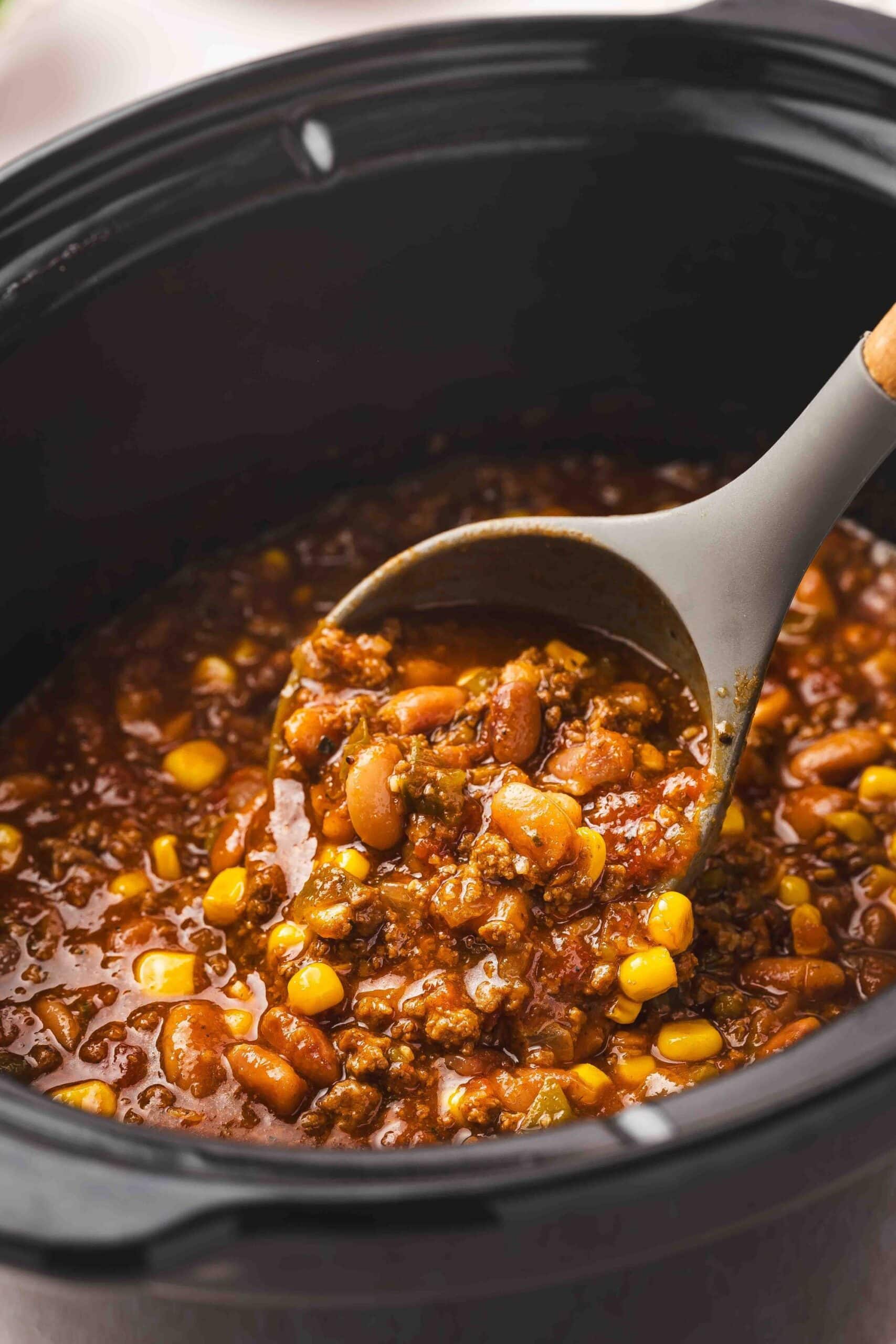 Close-up of hearty beef and bean chili cooking in a slow cooker with a thick, flavorful texture.