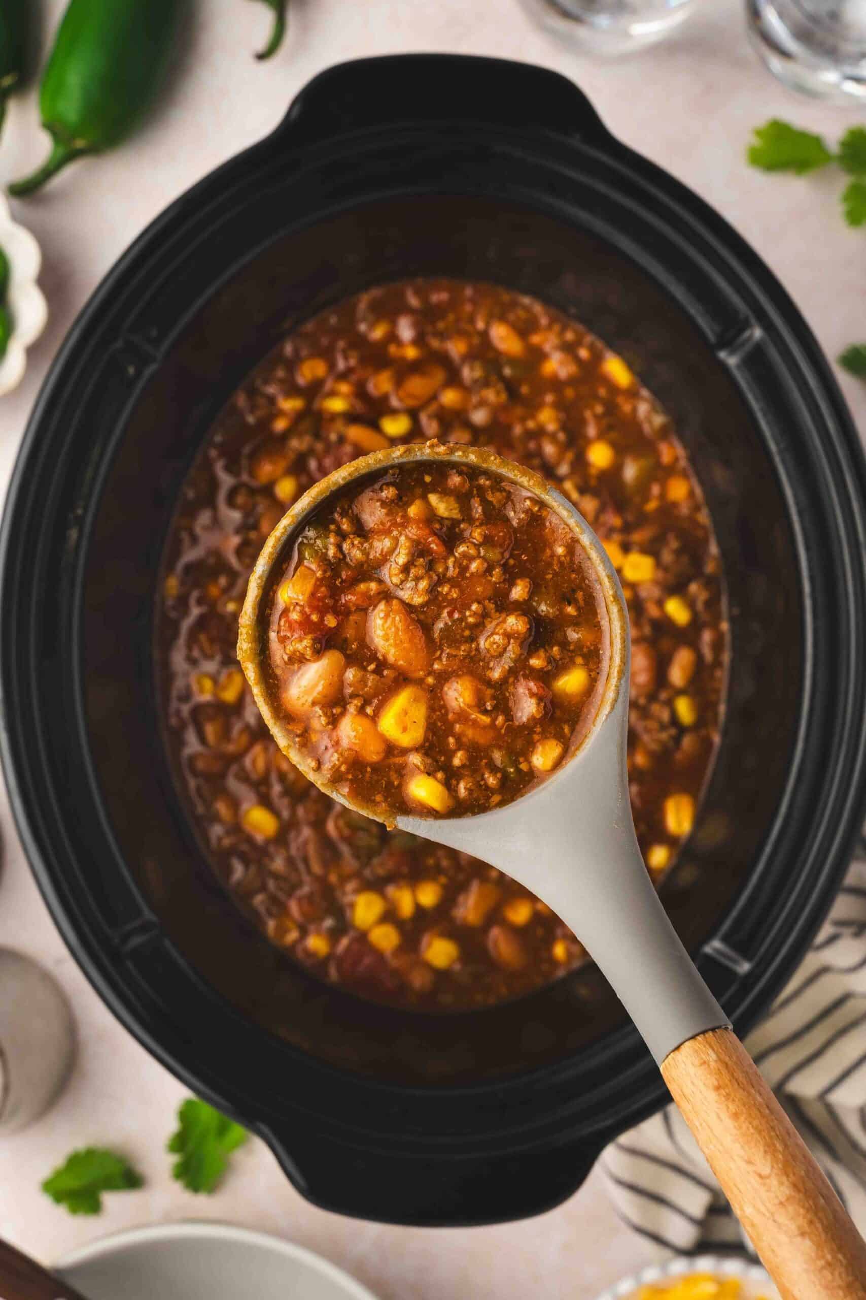 Southwest-style chili with ground beef, pinto beans, and vegetables cooking in a crockpot.
