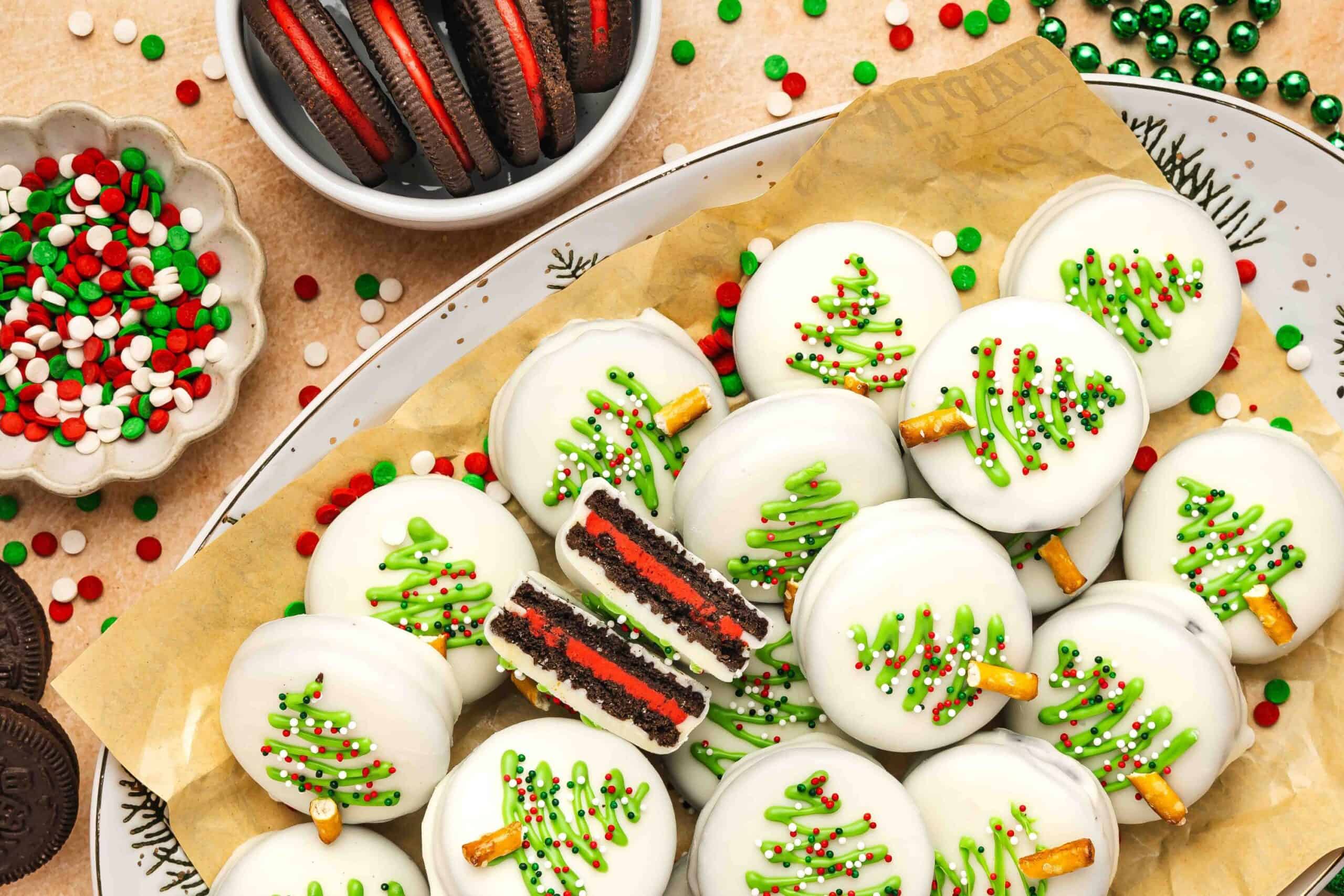 White chocolate covered Oreos with red cream filling displayed on a Christmas dessert tray.