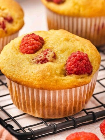 Fluffy muffins with a bite taken, showing soft texture and raspberries.